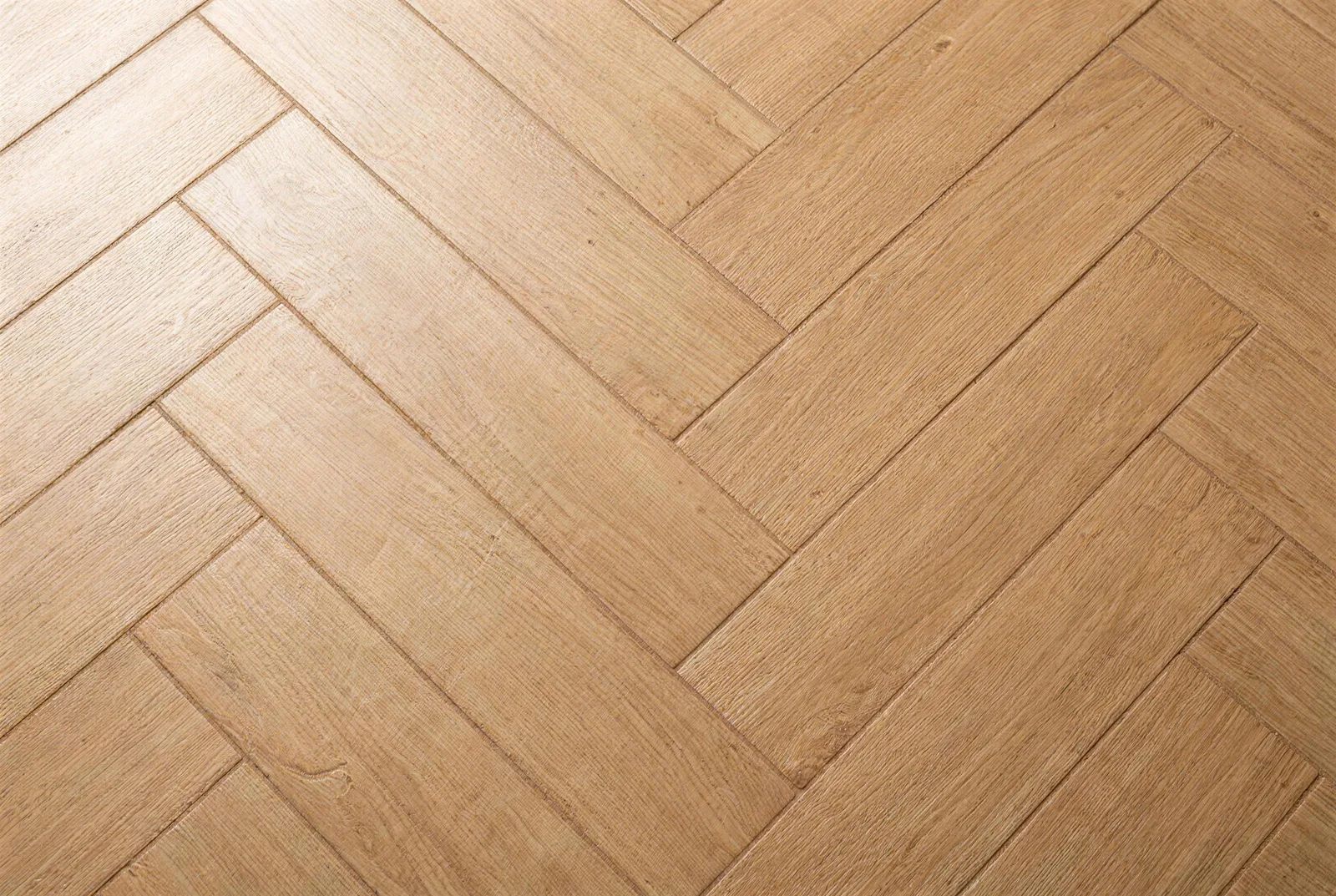 Macrotextuur van keramisch parket in visgraat: houtlook-tegels met strijklicht over de planken